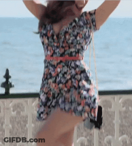 Woman In Floral Dress Dancing On Balcony Overlooking Ocean GIF