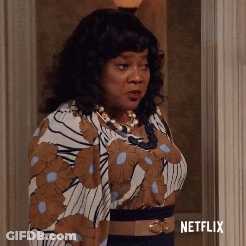 Woman In Floral Dress In Front Of Netflix Sign GIF
