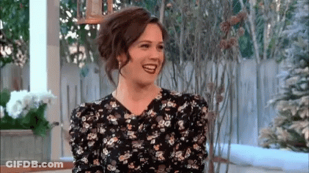 Woman In Floral Dress Smiling And Laughing On Porch GIF