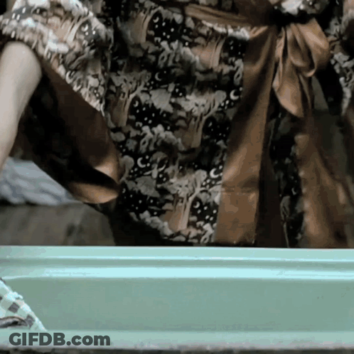 Woman In Floral Dress Standing In Front Of Green Box GIF