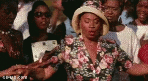 Woman In Floral Shirt And Hat Standing In Crowd GIF