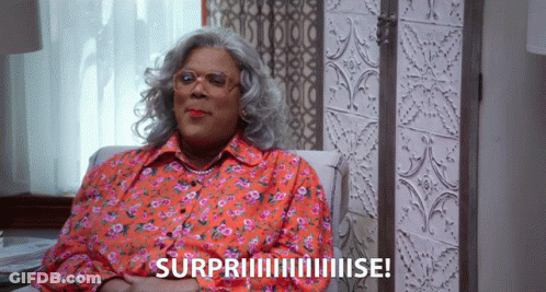 Woman In Floral Shirt Surprised On Couch GIF