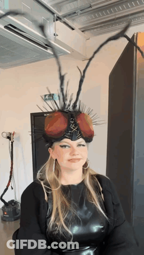 Woman In Fly Headpiece With Green Exit Sign GIF