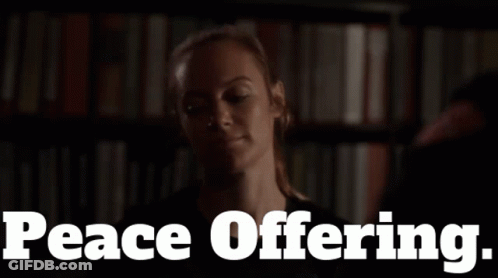 Woman In Front Of Bookshelf With Peace Offering GIF