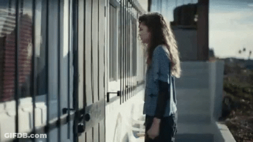 Woman In Front Of Building With Fence GIF