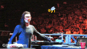 Woman In Front Of Crowd With Bee Flying GIF