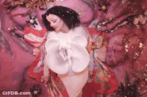 Woman In Front Of Pink Wall With White Flower GIF