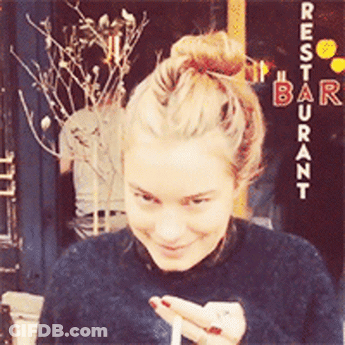 Woman In Front Of Restaurant Sign GIF