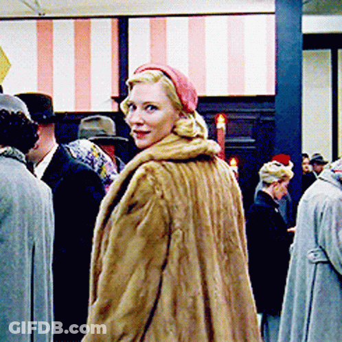 Woman In Fur Coat And Red Hat Standing In Crowd GIF