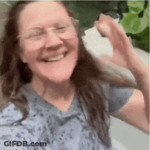 Woman In Glasses And Blue Shirt Smiling And Waving GIF