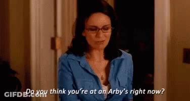 Woman In Glasses And Blue Shirt Talking By Door GIF