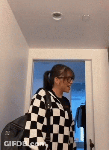 Woman In Glasses And Checkered Sweater Standing In Hallway GIF