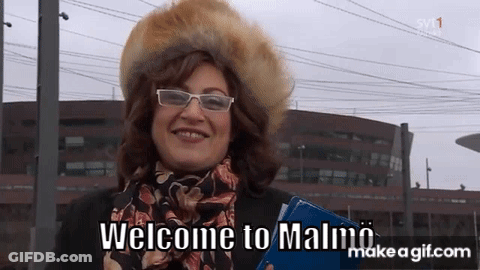 Woman In Glasses And Fur Hat Says Welcome To Malmo GIF