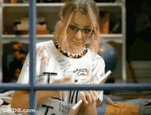 Woman In Glasses And T-Shirt Looking Out Window GIF