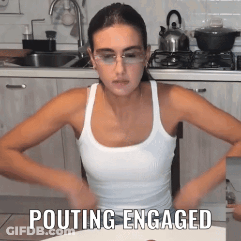 Woman In Glasses And Tank Top Pouting In Kitchen GIF