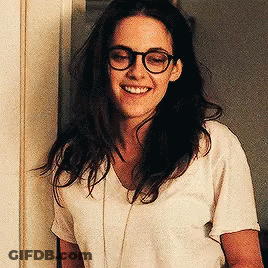 Woman In Glasses And White Shirt Smiling By Door GIF