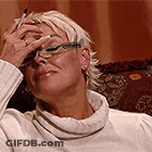 Woman In Glasses And White Sweater Holding Pen To Face GIF