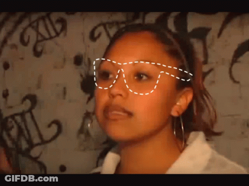 Woman In Glasses In Front Of Graffiti Saying XII GIF