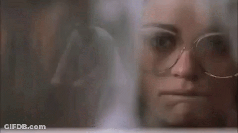 Woman In Glasses Looking Through Window GIF