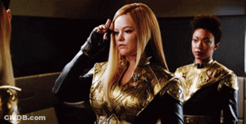 Woman In Gold And Black Outfit Next To Woman GIF