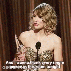 Woman In Gold Dress Holding Trophy And Microphone GIF