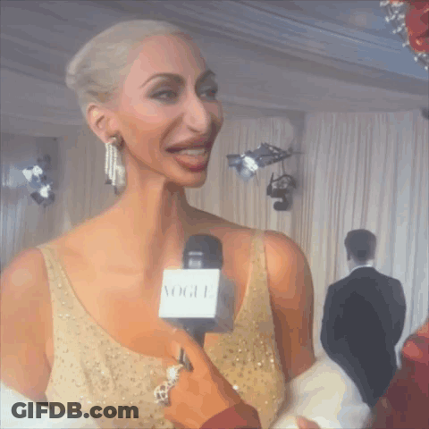 Woman In Gold Dress Interviewed With Vogue Microphone GIF