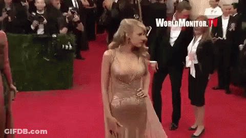 Woman In Gold Dress Walking Red Carpet With Man In Tuxedo GIF