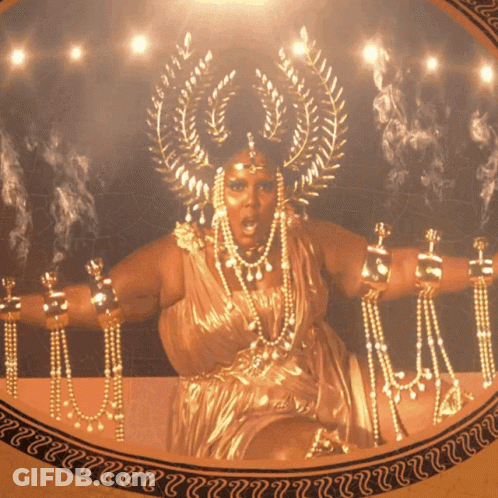 Woman In Gold Dress With Crown Surrounded By Gold Jewelry GIF