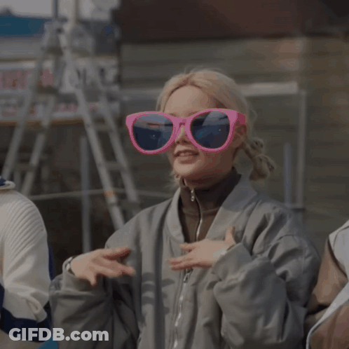 Woman In Gray Jacket And Pink Sunglasses Making Heart With Hands GIF