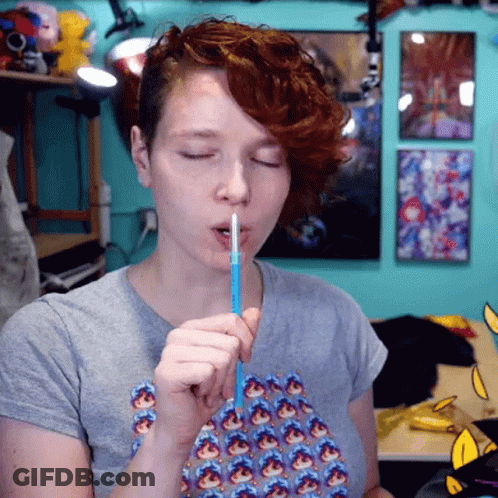 Woman In Gray Shirt Holding Straw In Mouth GIF