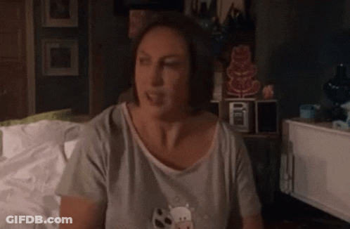 Woman In Gray Shirt Sitting On Bed GIF