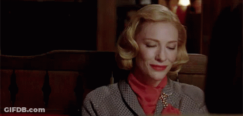 Woman In Gray Suit And Red Sweater Smiling On Bench GIF