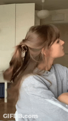 Woman In Gray Sweatshirt Holding Ponytail GIF