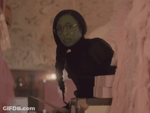 Woman In Green Dress And Green Hat Sitting On Couch GIF