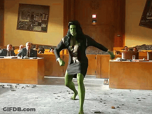 Woman In Green Dress Dancing Before Suited Group GIF
