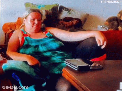 Woman In Green Dress Sitting On Couch With Legs Crossed GIF