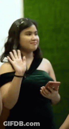 Woman In Green Dress Waving Holding Cell Phone GIF