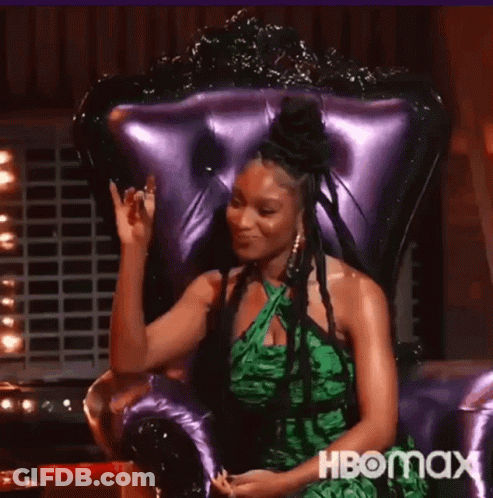 Woman In Green Dress Waving In Purple Chair GIF