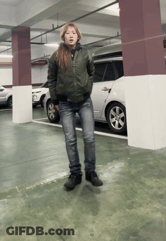 Woman In Green Jacket And Jeans In Parking Lot GIF