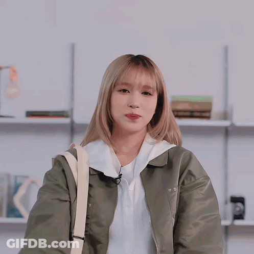 Woman In Green Jacket And White Shirt Waves GIF