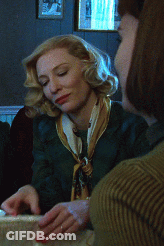 Woman In Green Jacket And Yellow Scarf Sitting With Another Woman GIF