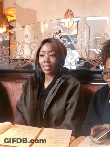 Woman In Green Jacket At Table With Menu GIF
