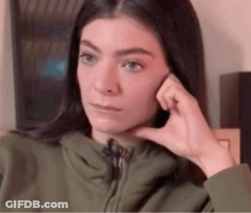 Woman In Green Jacket Hand To Ear Funny Face GIF