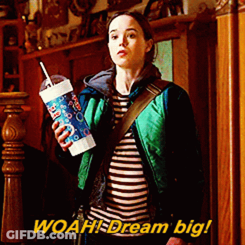 Woman In Green Jacket Holding Cup Saying Woah Dream Big GIF
