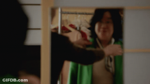 Woman In Green Jacket Smiling At Mirror GIF