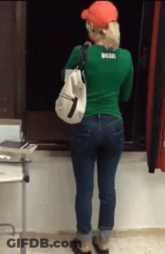 Woman In Green Shirt And Blue Jeans Holding White Bag GIF