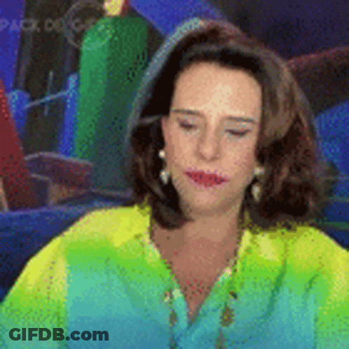 Woman In Green Shirt And Earrings Sitting In Front Of Mirror GIF