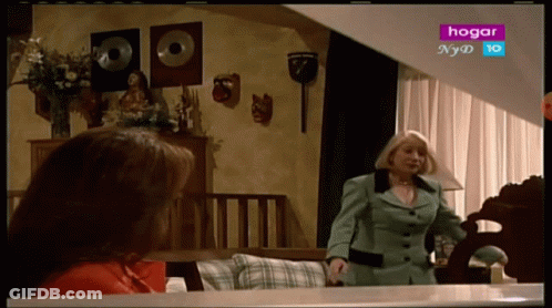 Woman In Green Suit In Front Of TV Saying Hogar GIF