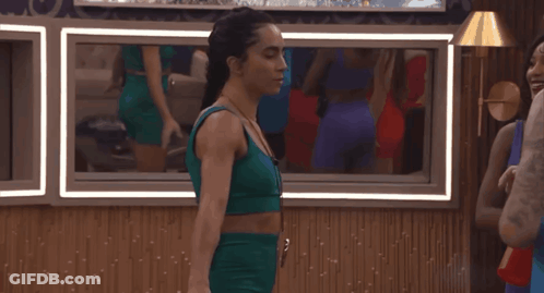 Woman In Green Top Standing Before Mirror GIF