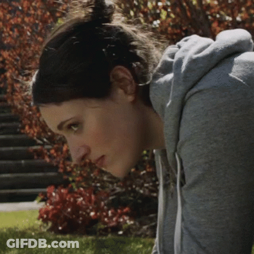 Woman In Grey Hoodie Looking Down At Camera GIF